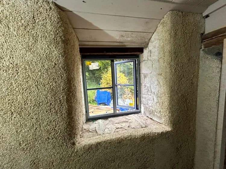 Sprayed hempcrete wrapping a window reveal in a stone wall retrofit