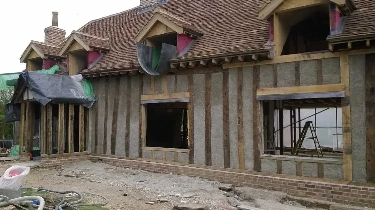 Spray-applied hempcrete tight against oak timber studs, pre-plaster