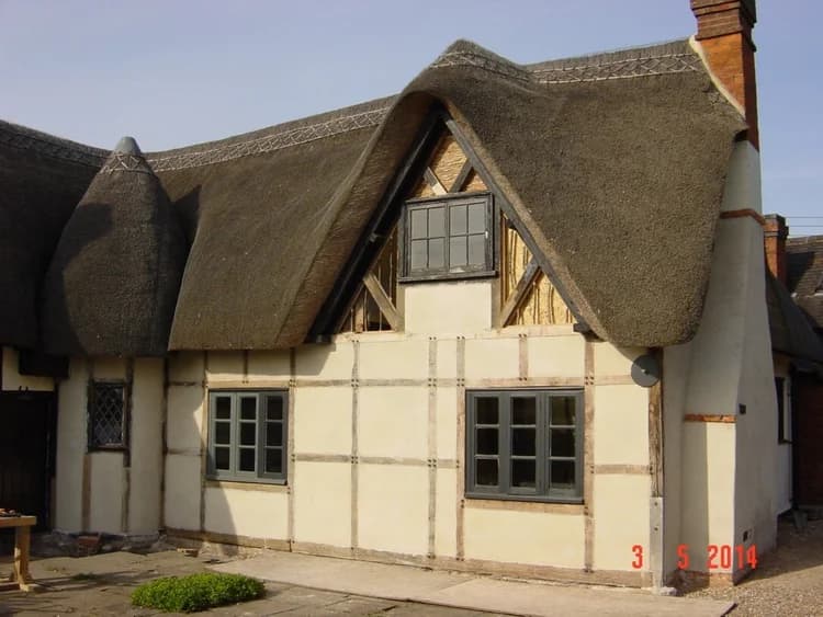 Lime-rendered exterior of a restored listed timber-framed cottage